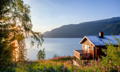 Norwegian wooden summer house (Hytte) with terrace overlooking scenic lake at sunset, Telemark, Norway, Scandinavia